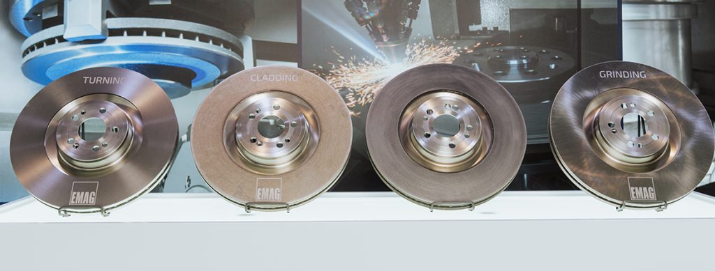 The image shows four brake discs in different manufacturing states: after turning, after laser metal deposition of the adhesion layer, after laser metal deposition of the friction layer and after grinding.