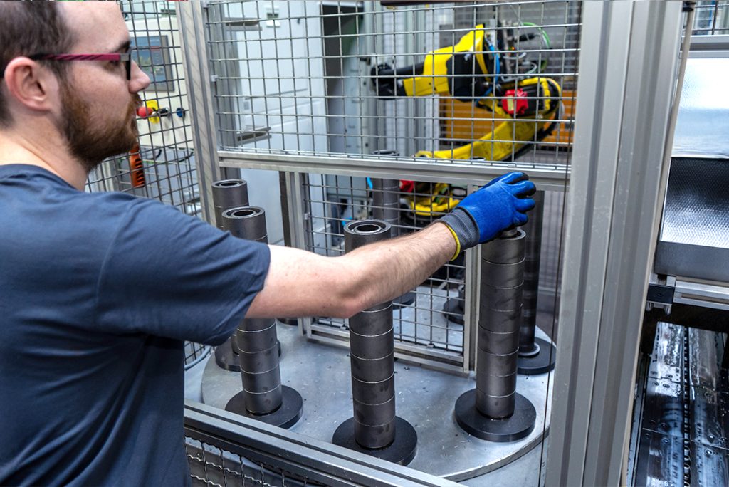 Facharbeiter bedient Werkstücke an einer automatisierten EMAG VL 2-Fertigungszelle mit Robotertechnik hinter Sicherheitsgittern.