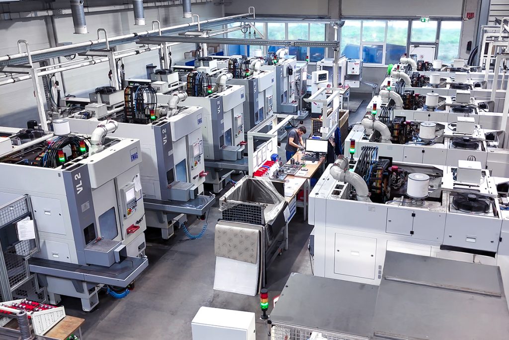 Vogelperspektive einer großen Produktionshalle mit zahlreichen weißen EMAG Drehmaschinen in Reihen, die die umfangreiche Fertigungskapazität der PENN GmbH mit insgesamt 43 Spindeln demonstriert.