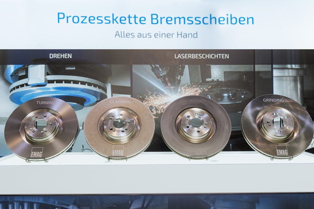 Die Aufnahme zeigt vier Bremsscheiben in unterschiedlichen Fertigungszuständen: nach dem Drehen, nach dem Laserbeschichten der Haftschicht, nach dem Laserbeschichten der Reibschicht und nach dem Schleifen.